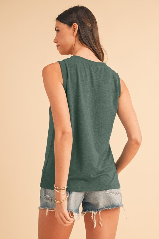 Woman wearing a green sleeveless top and denim shorts on a beige background