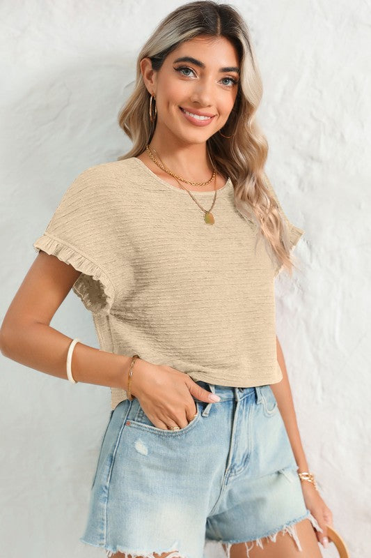 Woman wearing a beige top and denim shorts against a white background