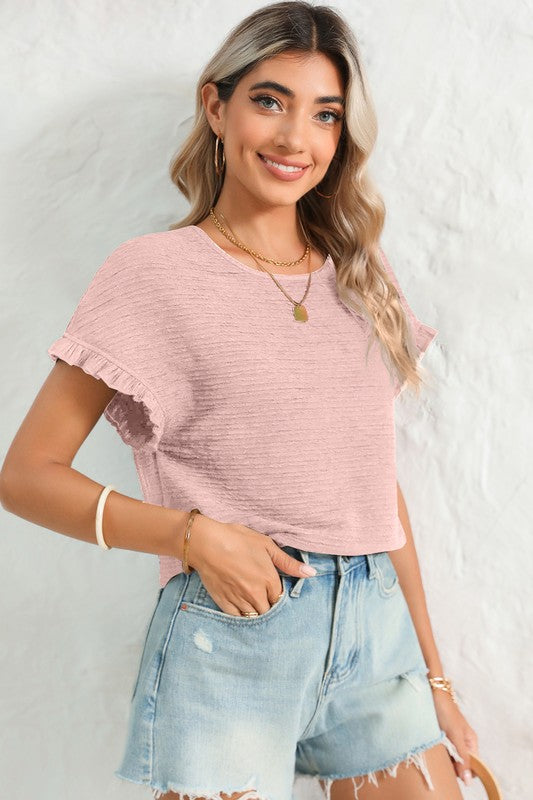 Woman wearing a pink top and denim shorts against a white background