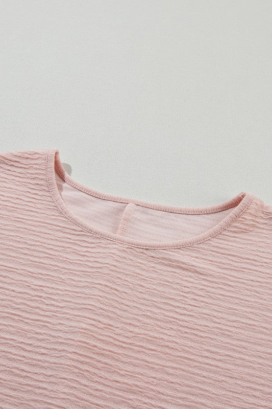 Close-up of a pink ribbed sweater on a light gray background