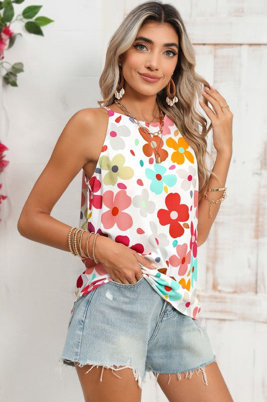 Woman wearing a colorful floral sleeveless top and denim shorts against a light background