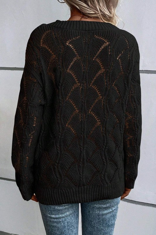 Person wearing a black patterned sweater with a white wall background