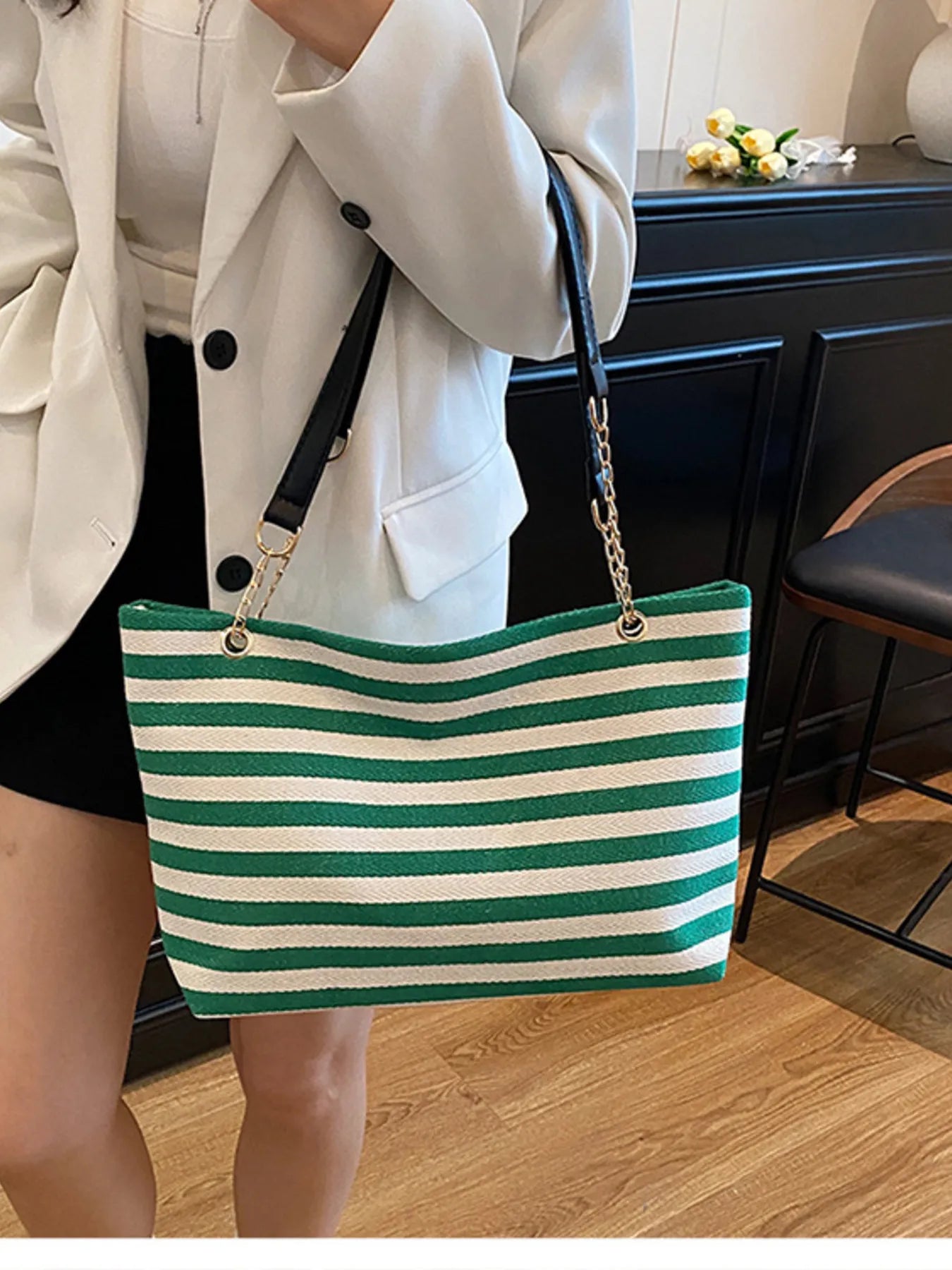 Person holding a green and white striped bag indoors.