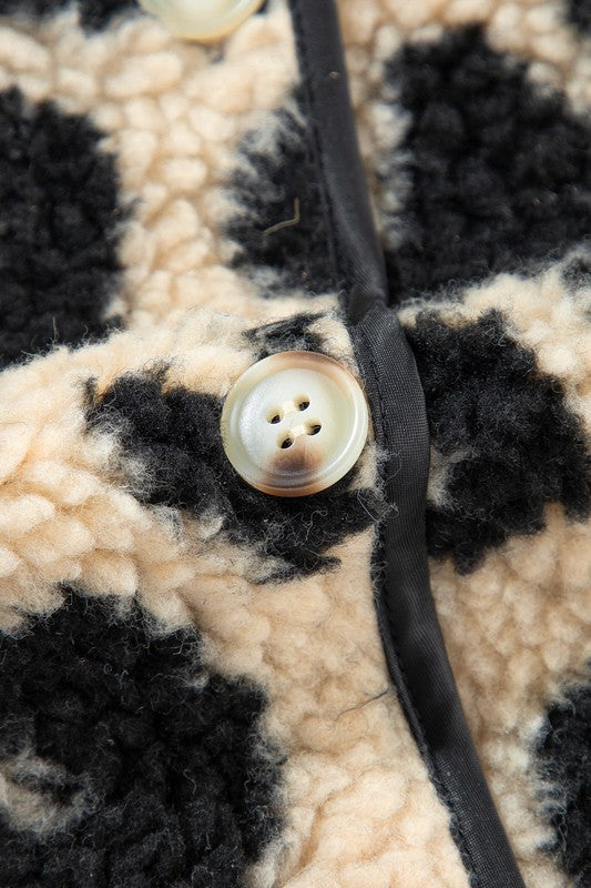 Close-up of a button on a textured fabric with black and beige pattern