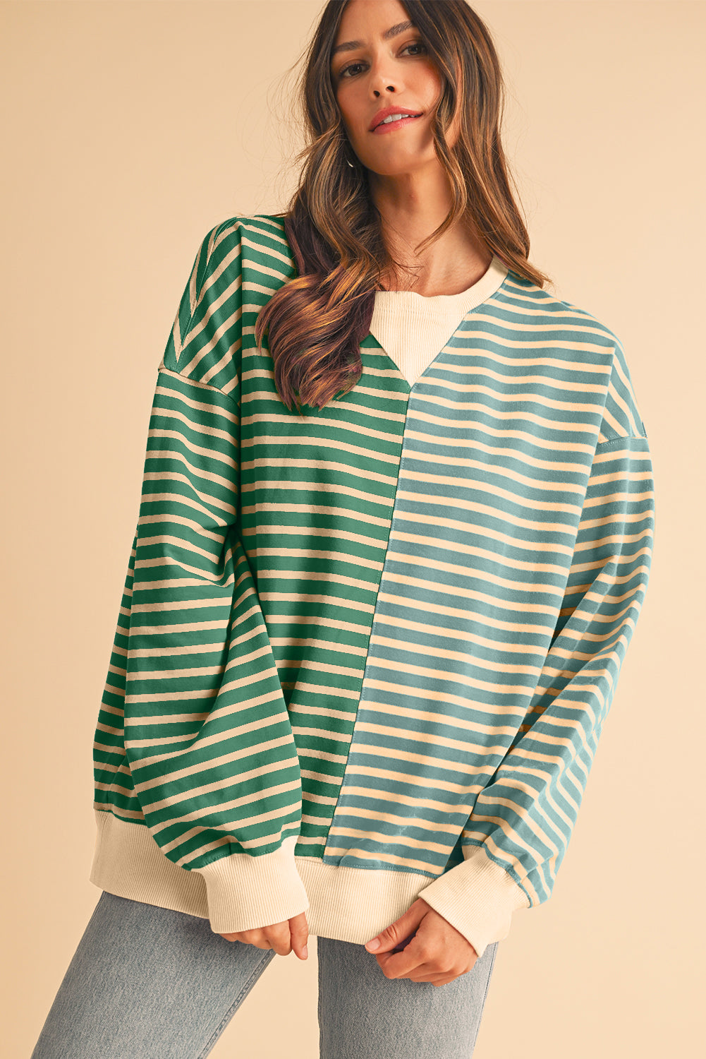 Woman wearing a green and blue striped sweater on a beige background