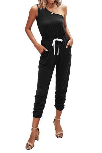 Woman wearing a black one-shoulder jumpsuit with a white belt on a white background
