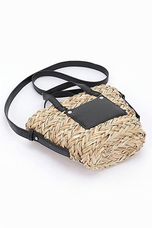 Woven handbag with a black strap and flap on a white background