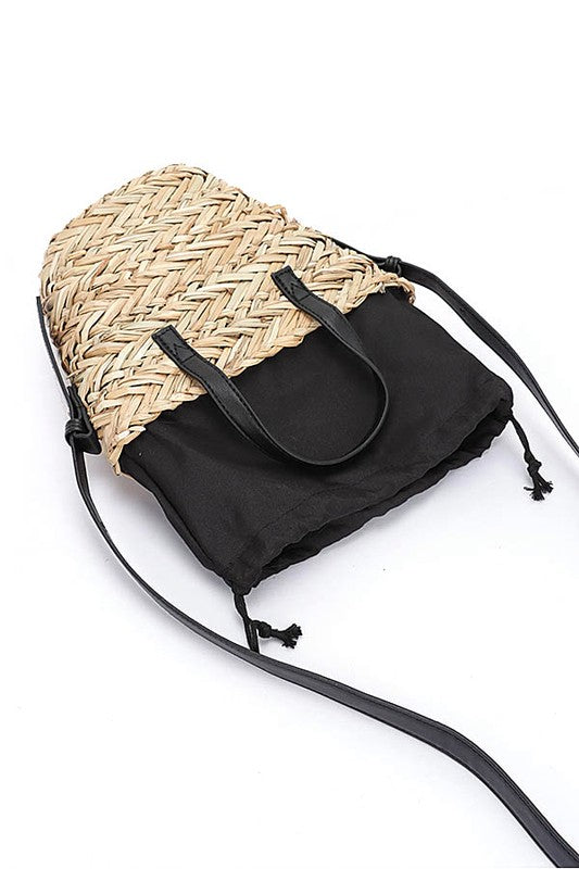 Black drawstring bag with woven straw top section on a white background