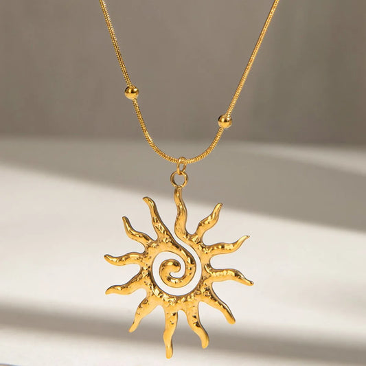 Gold sun-shaped pendant necklace on a neutral background