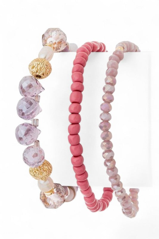 Set of three beaded bracelets with pink, gold, and purple beads on a white background