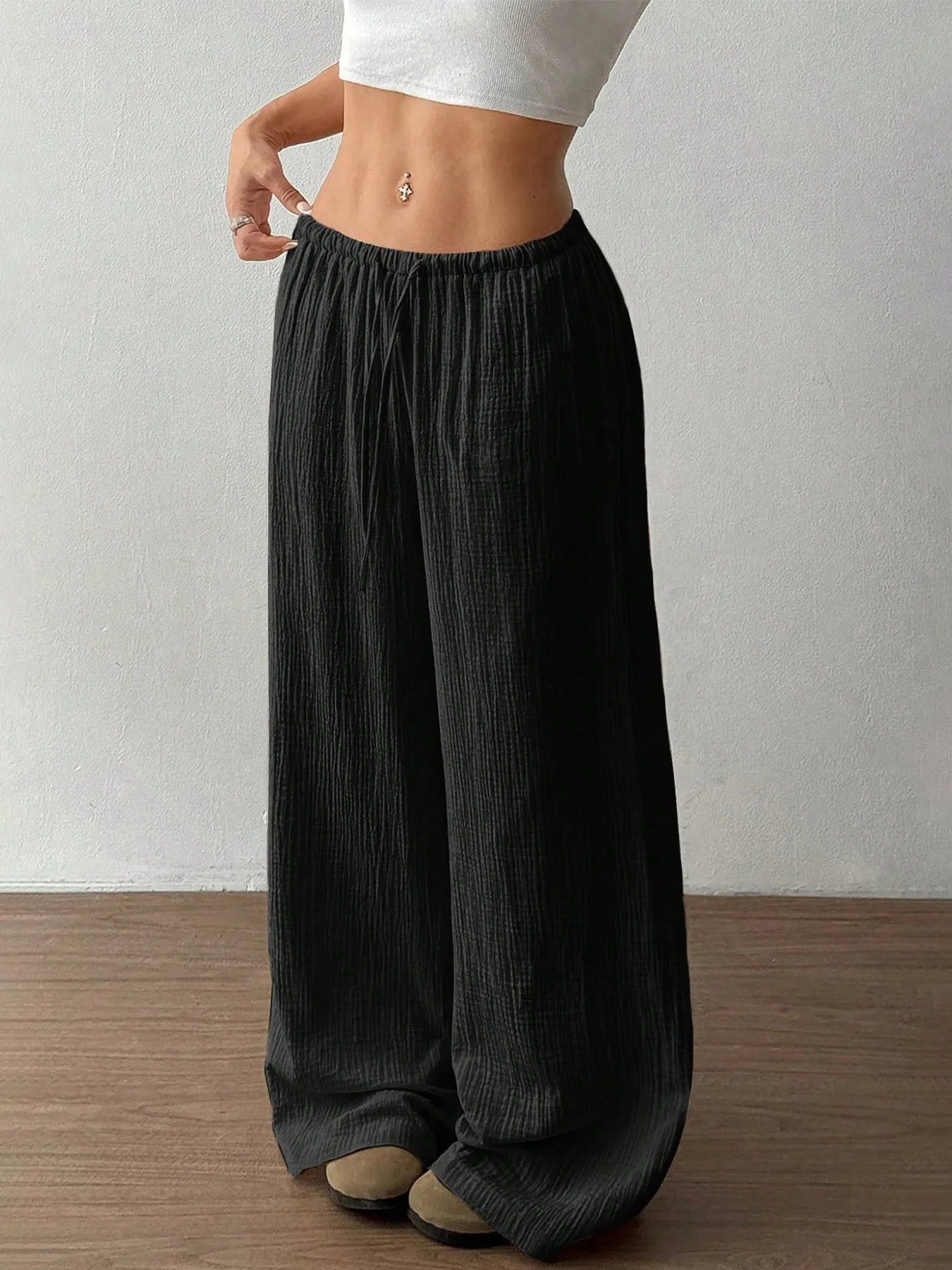 Person wearing black wide-leg pants against a plain background