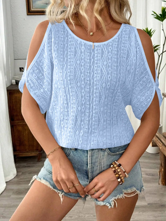 Woman wearing a light blue top and denim shorts indoors.