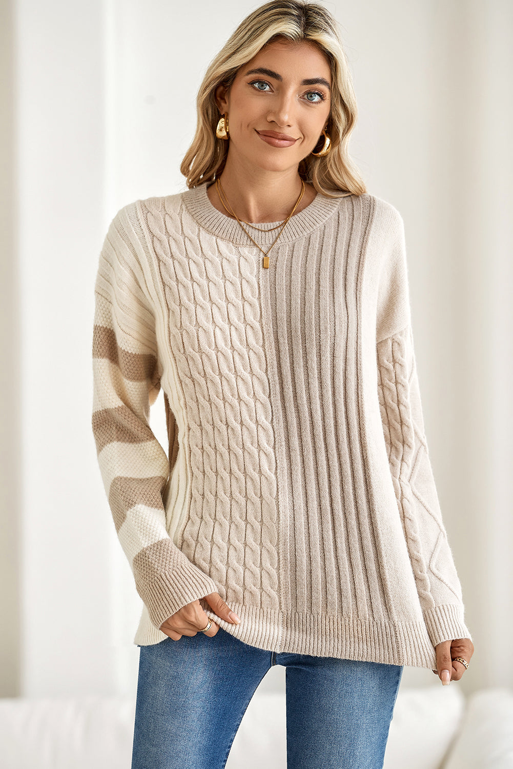Woman wearing a beige cable knit sweater with a neutral background