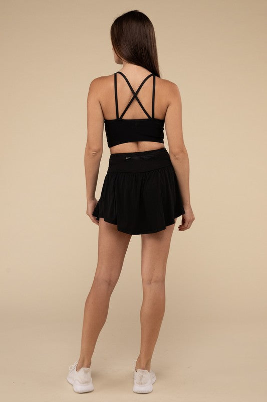 Woman wearing a black sports bra and skirt set on a beige background