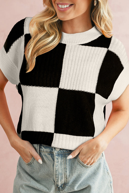 Person wearing a black and white checkered sweater against a pink background
