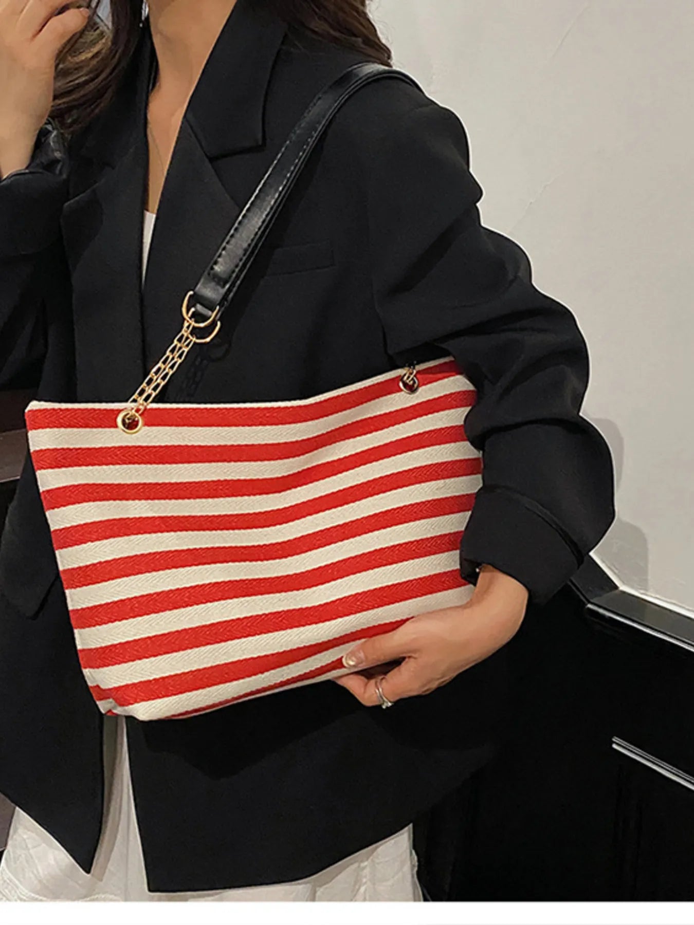 Person holding a red and white striped bag with a black background