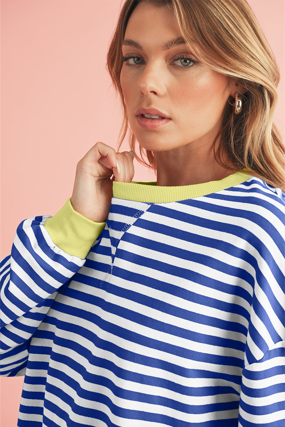 Woman wearing a blue and white striped sweater with a pink background