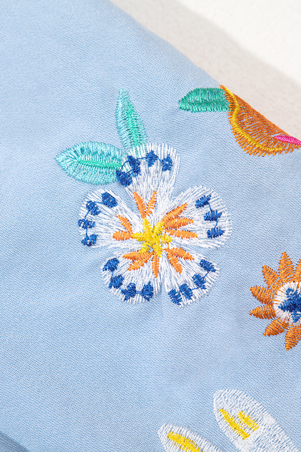 Embroidered floral design on a light blue fabric background