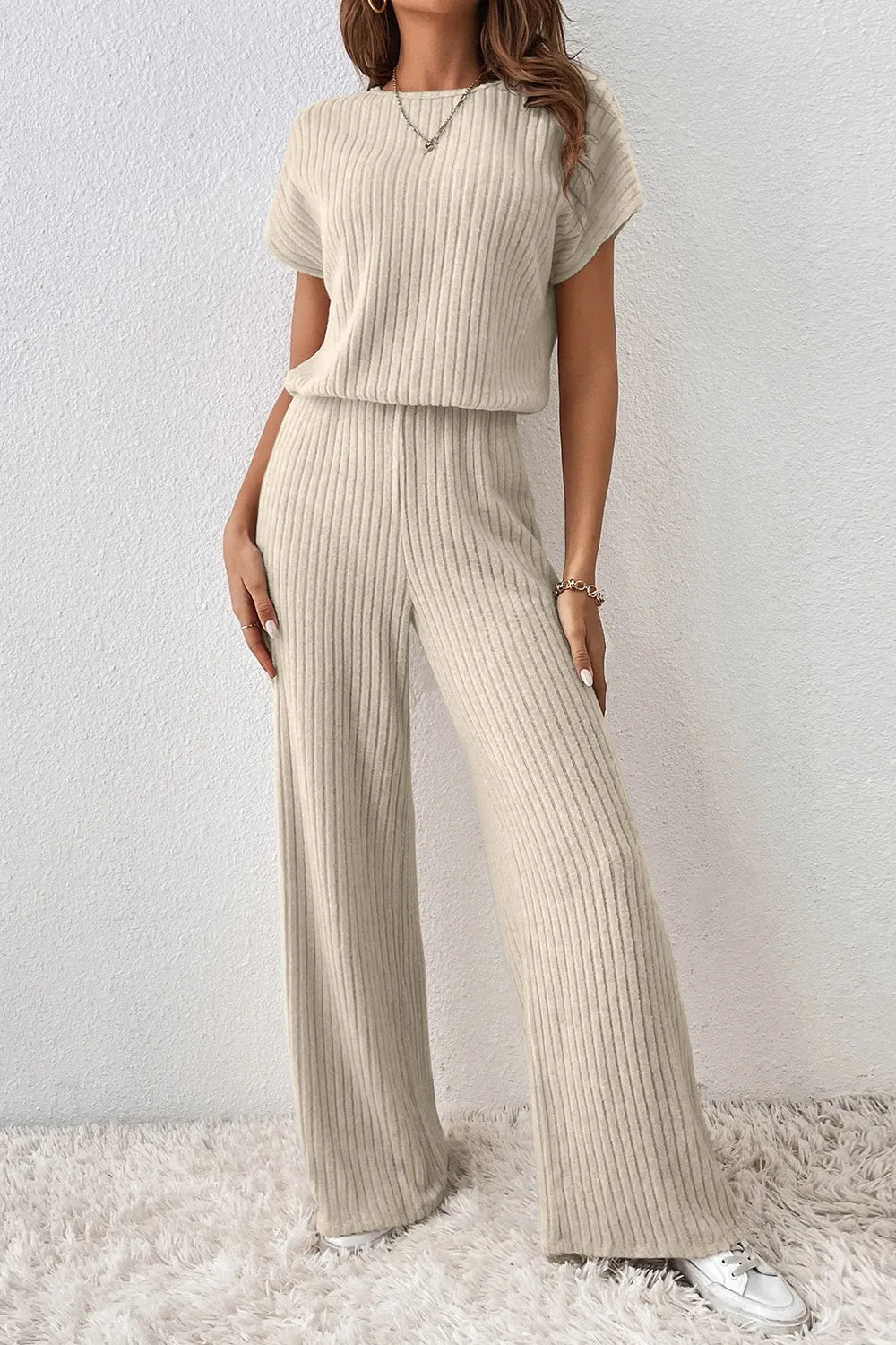 Person wearing a beige ribbed knit outfit against a white background