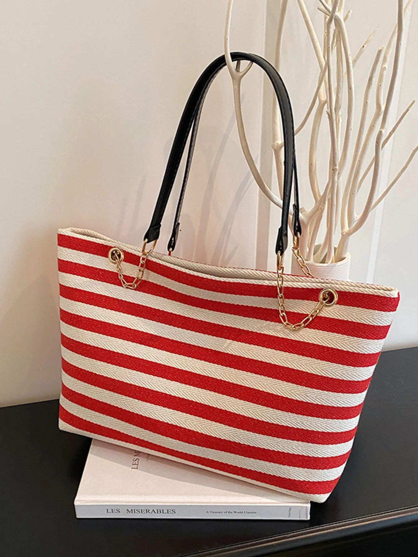 Red and white striped tote bag on a black surface with a blurred background