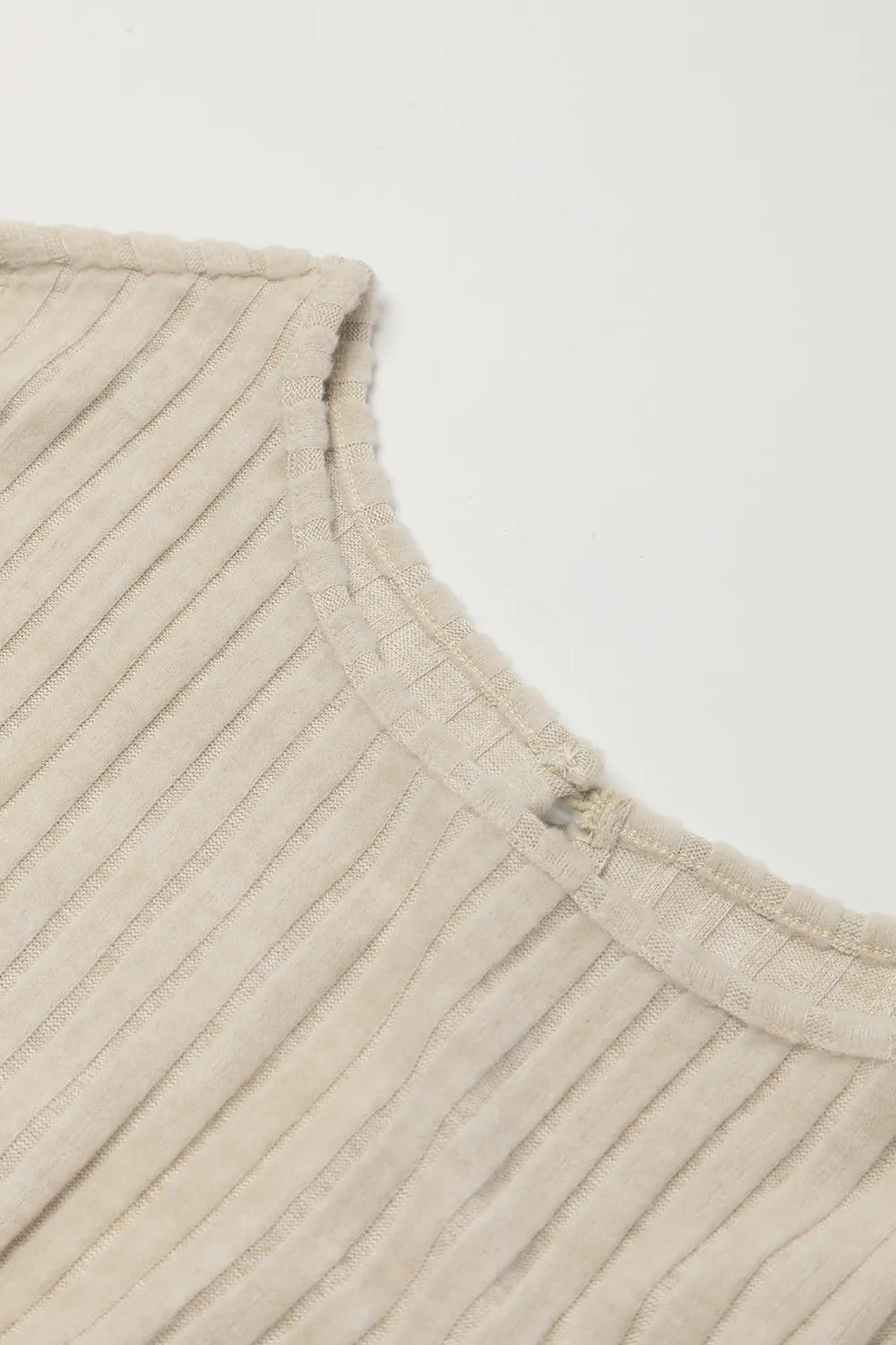 Close-up of beige fabric with a subtle pattern on a light gray background