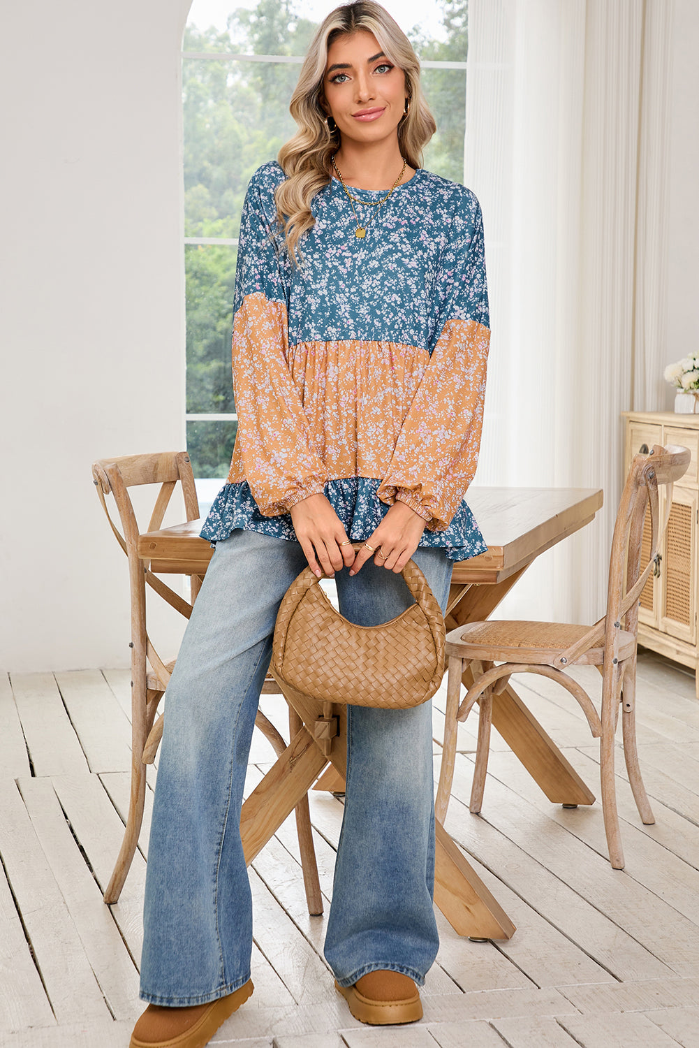 Woman wearing a blue and orange patterned top with jeans, sitting on a wooden chair indoors.