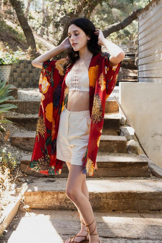 Woman in a colorful kimono standing on outdoor steps with trees and a building in the background