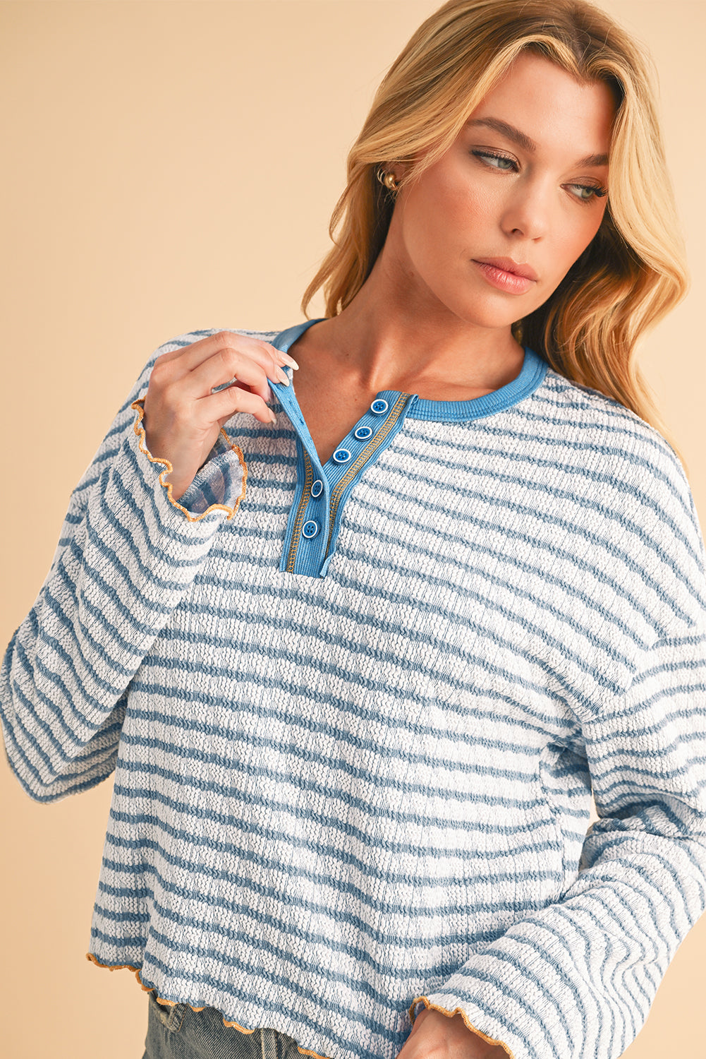 Woman wearing a blue and white striped sweater against a beige background