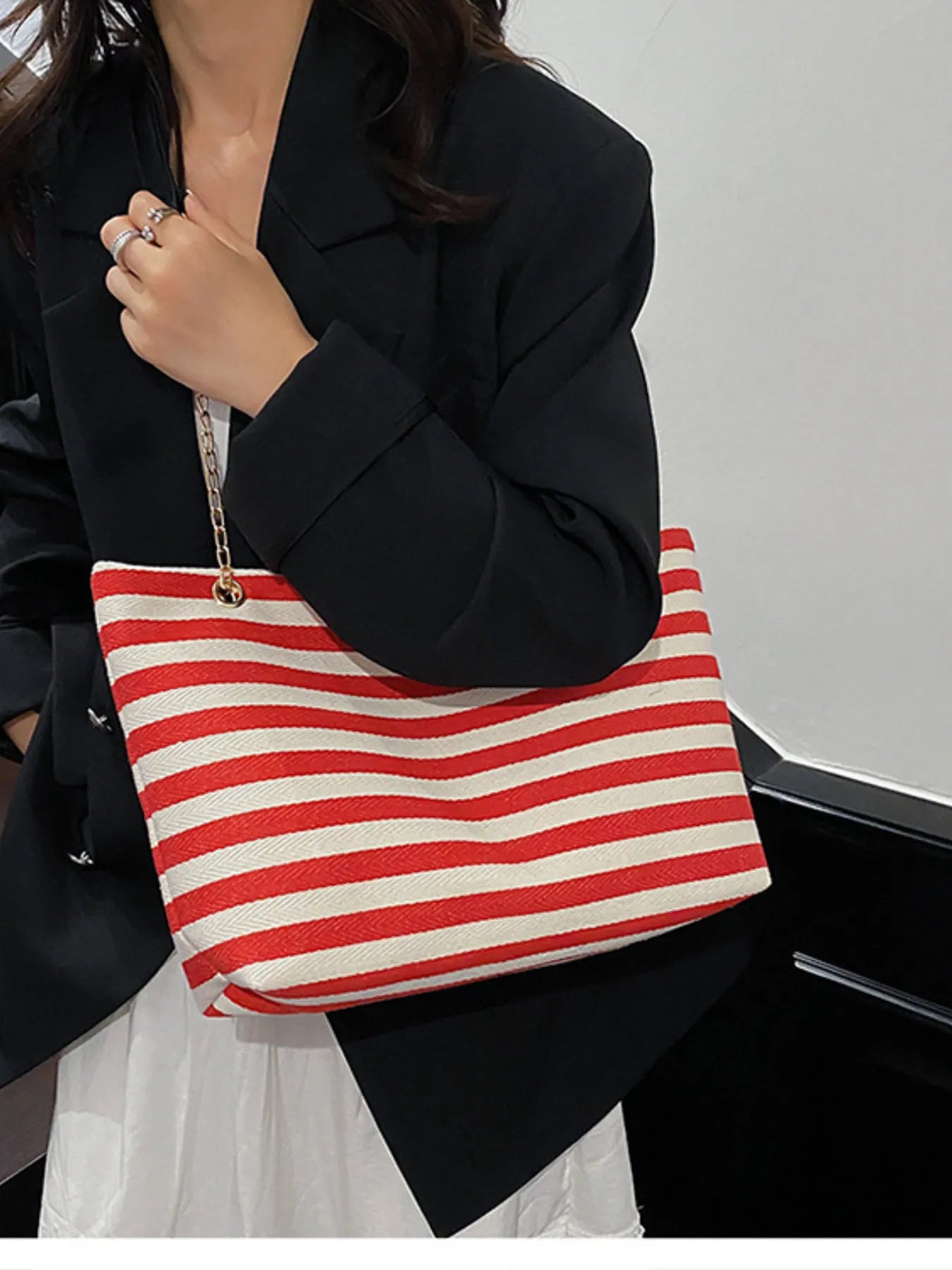 Person holding a red and white striped bag against a neutral background