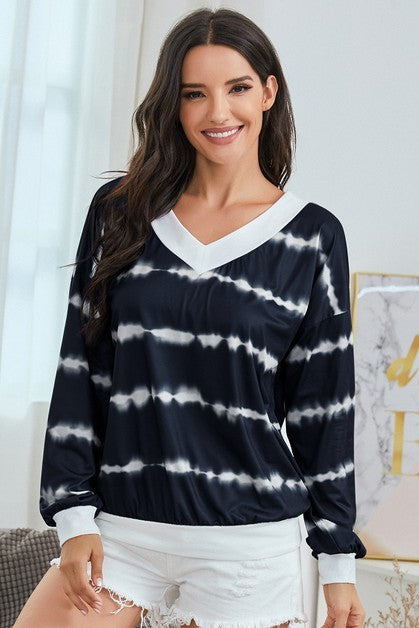 Woman wearing a navy and white tie-dye long-sleeve top in a bright room.