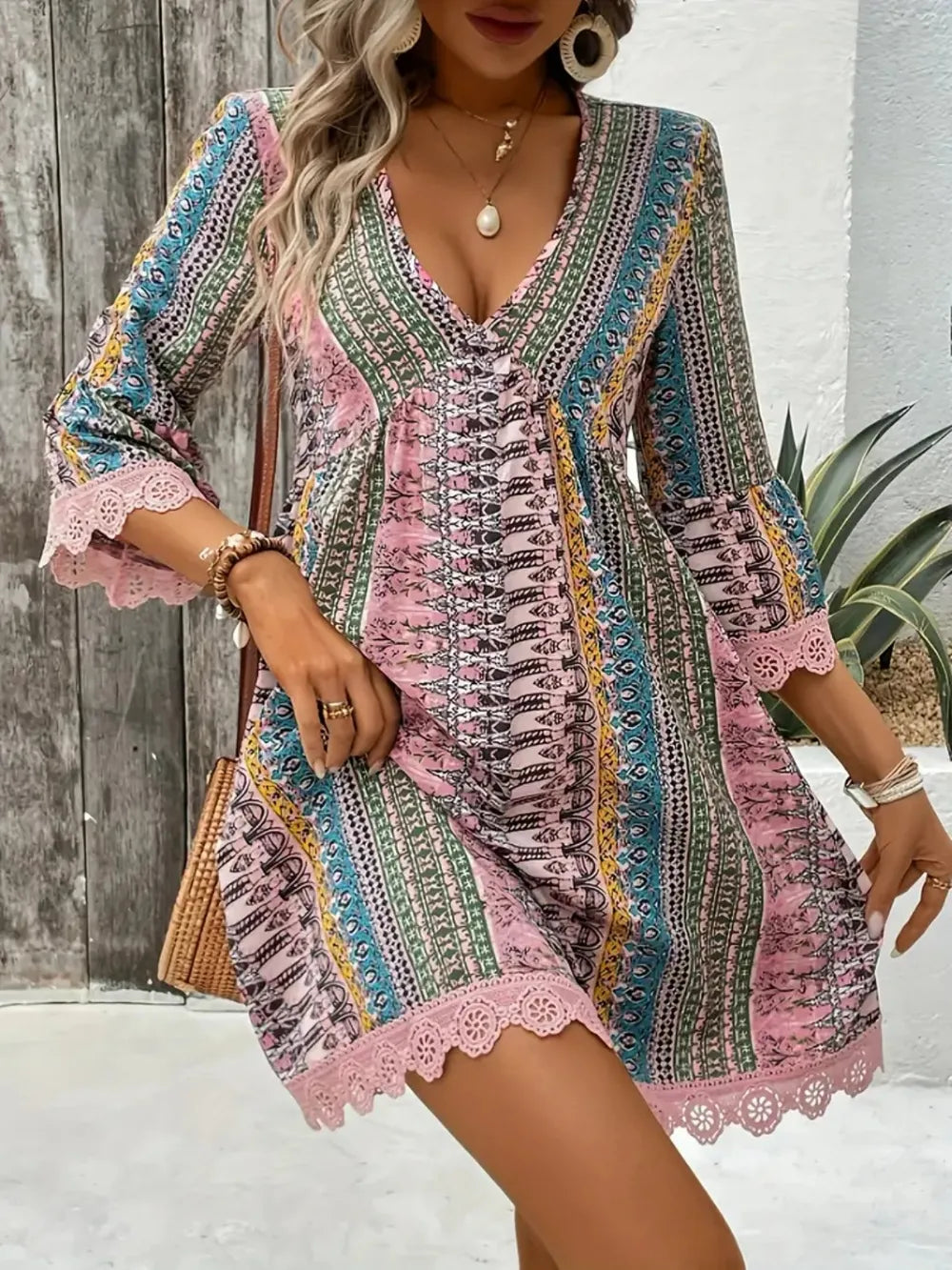 Woman wearing a colorful patterned dress with lace details against a wooden wall.