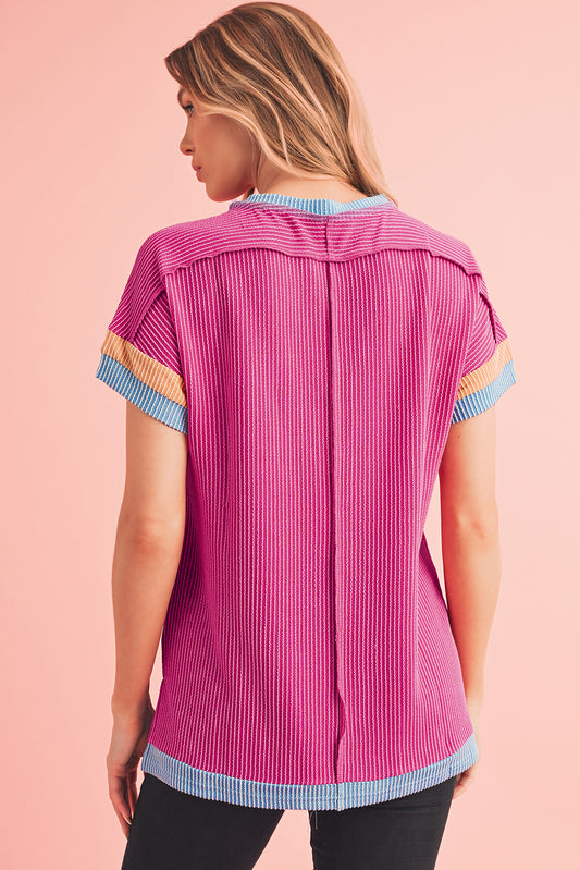 Woman wearing a pink striped shirt with colorful sleeves on a pink background