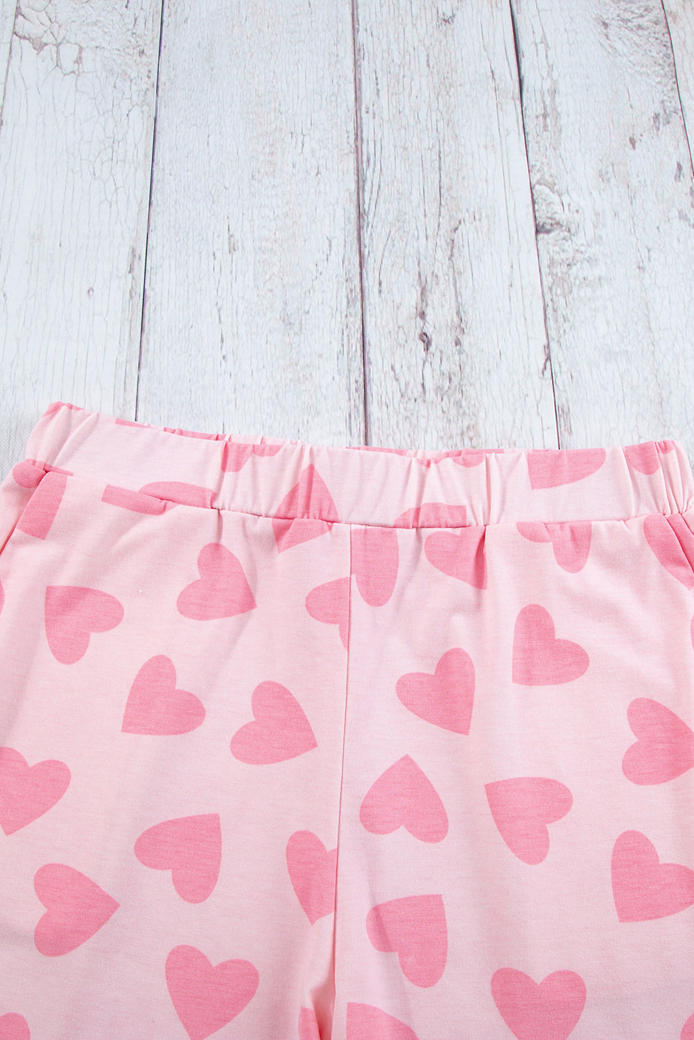 Pink shorts with heart patterns on a light wooden surface