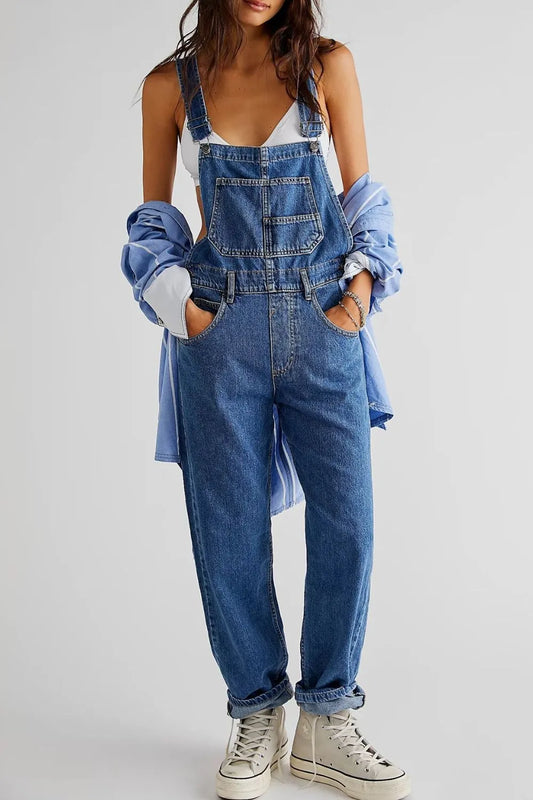 Person wearing blue denim overalls with a plain background