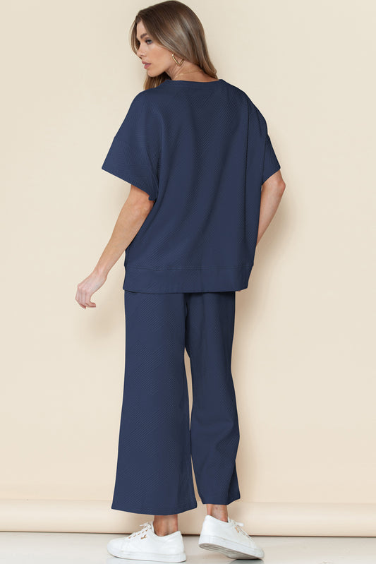 Woman wearing a navy blue outfit with wide-leg pants against a beige background