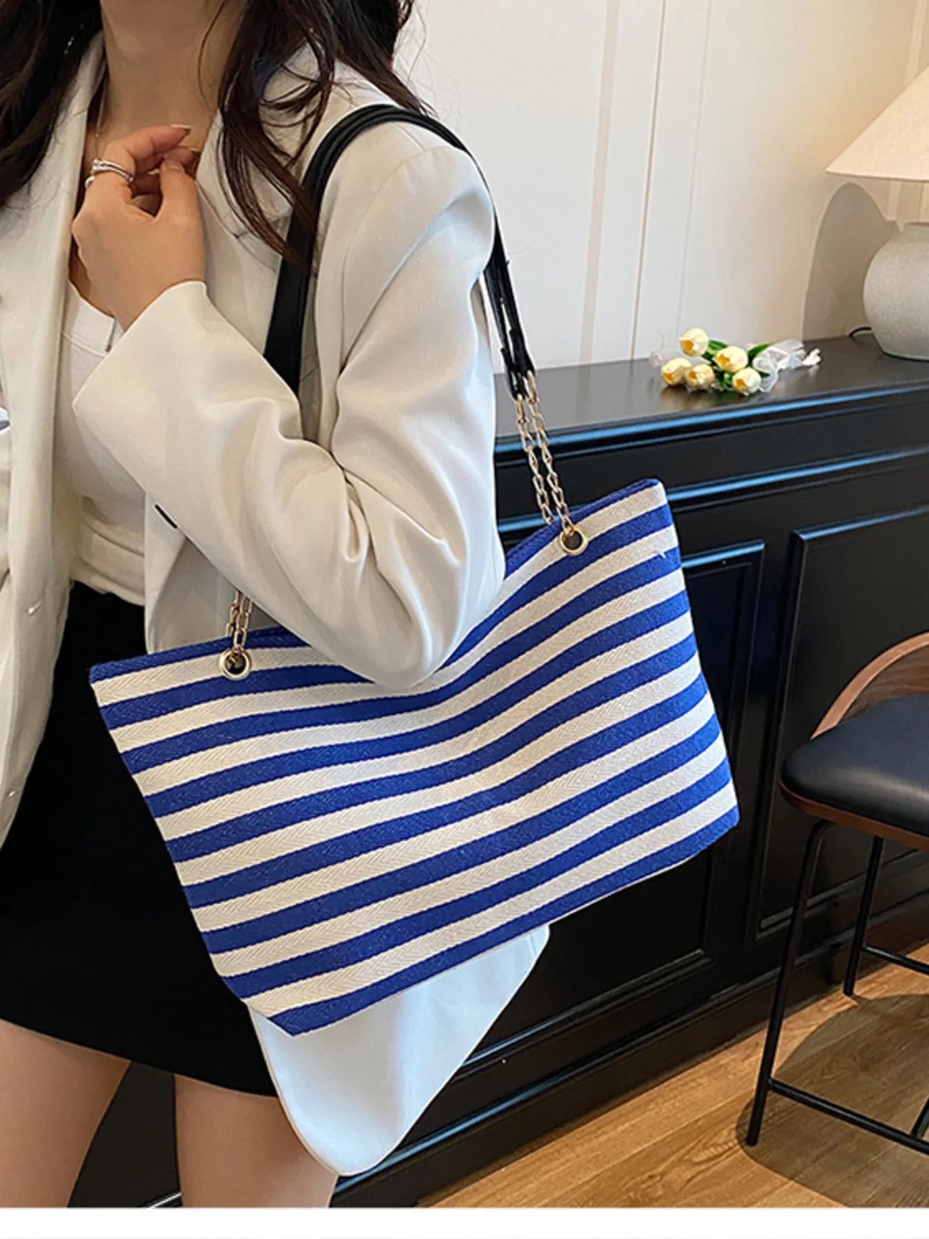 Person holding a blue and white striped bag indoors.