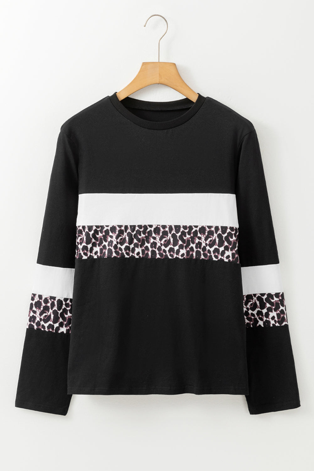 Black long-sleeve top with white and leopard print accents on a hanger against a white background