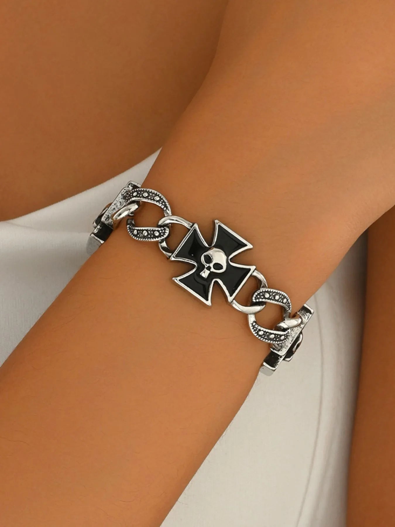 Bracelet with a black and silver clasp on a wrist against a neutral background