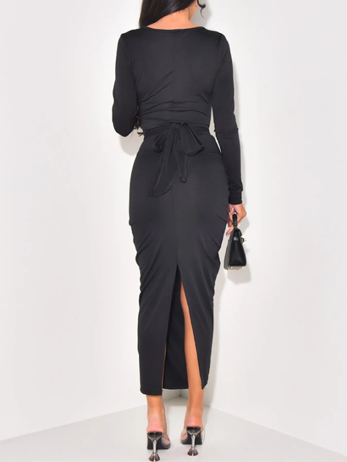 Black long-sleeve dress with a tie detail and high slit on a white background