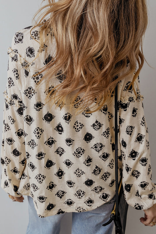 Person wearing a floral blouse with black patterns on a plain background