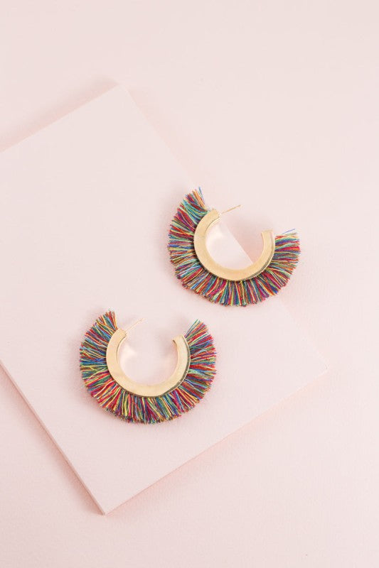 Colorful hoop earrings on a pink surface