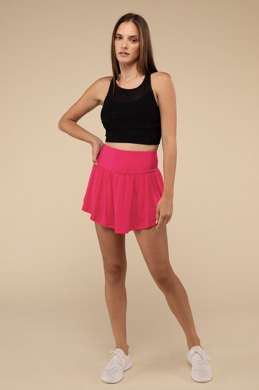 Woman wearing a black crop top and pink skirt on a beige background