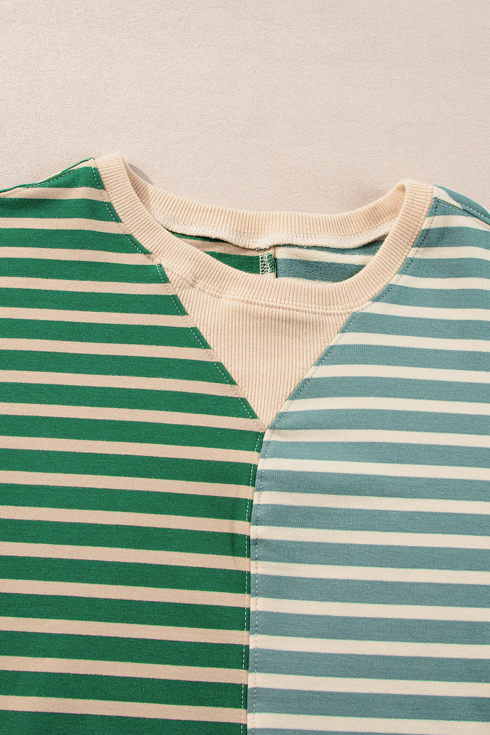Striped garment with green and blue horizontal stripes on a beige background