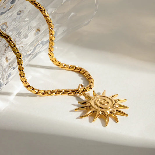 Gold necklace with a sun pendant on a light background