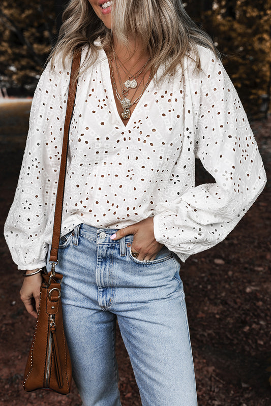 Woman wearing a white blouse with black polka dots and blue jeans, holding a brown leather bag.