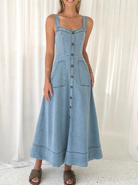 Woman wearing a blue denim dress with buttons against a white curtain background