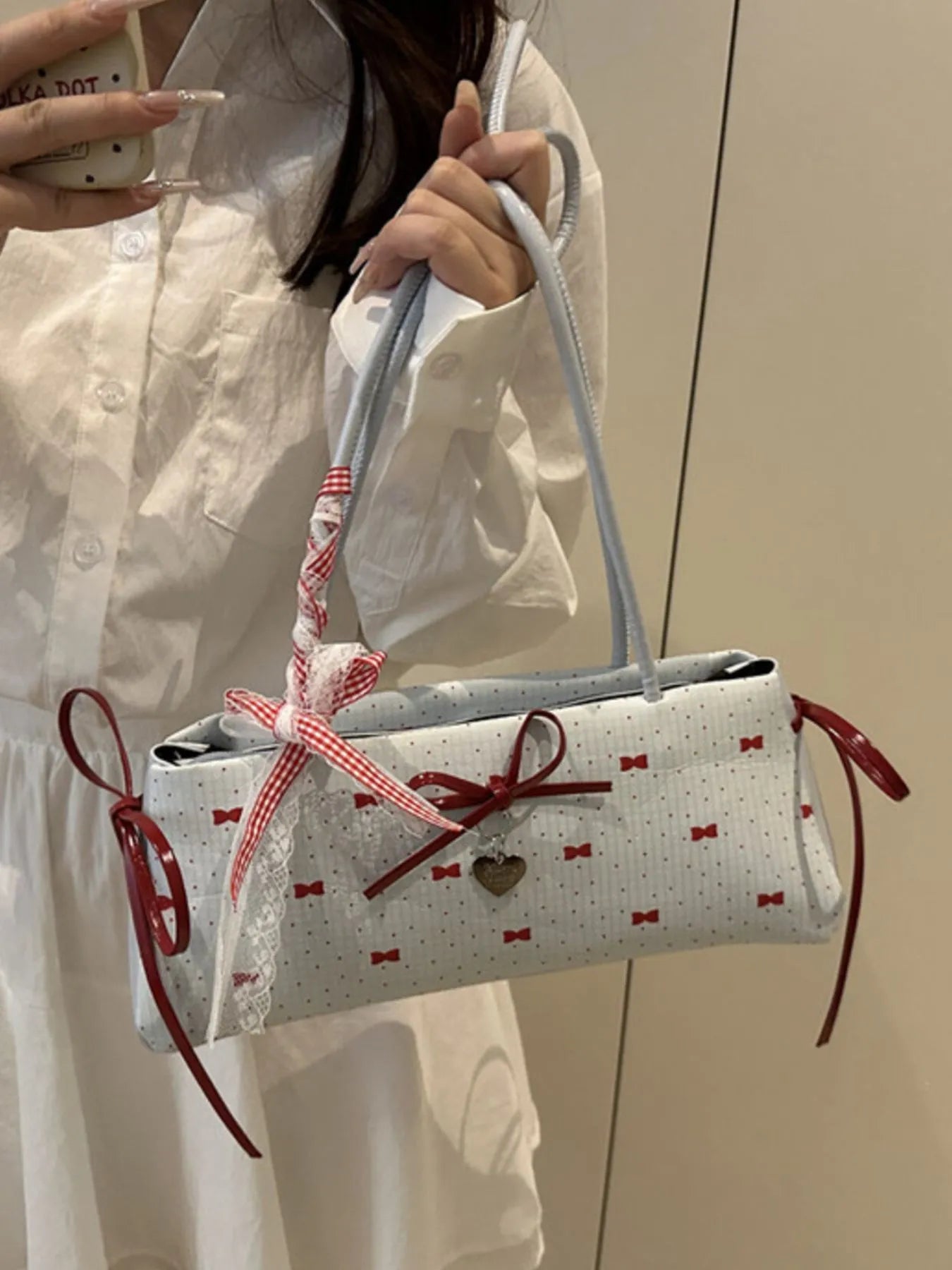 Person holding a white handbag with red accents and patterns against a neutral background