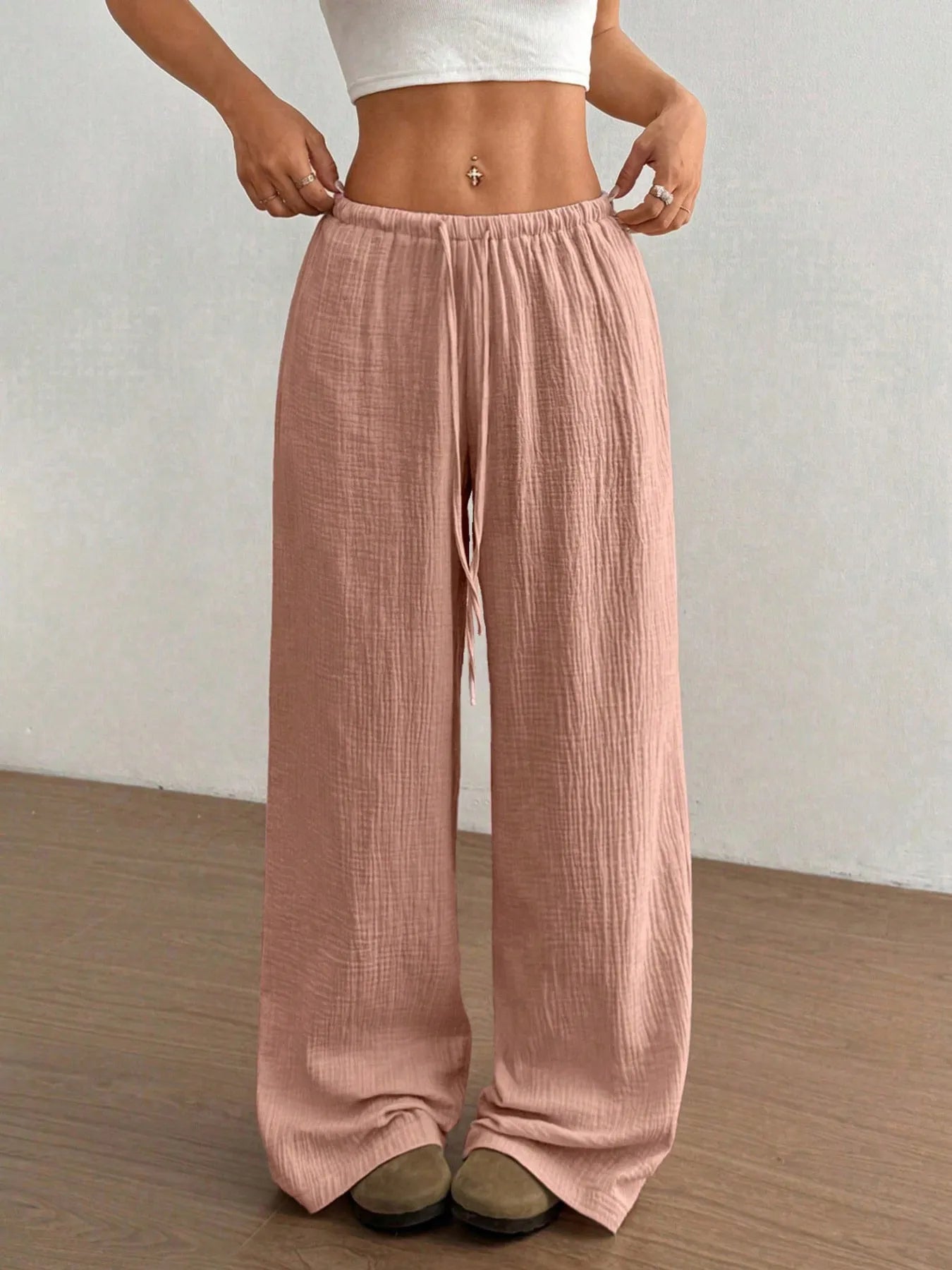 Person wearing pink wide-leg pants against a plain background