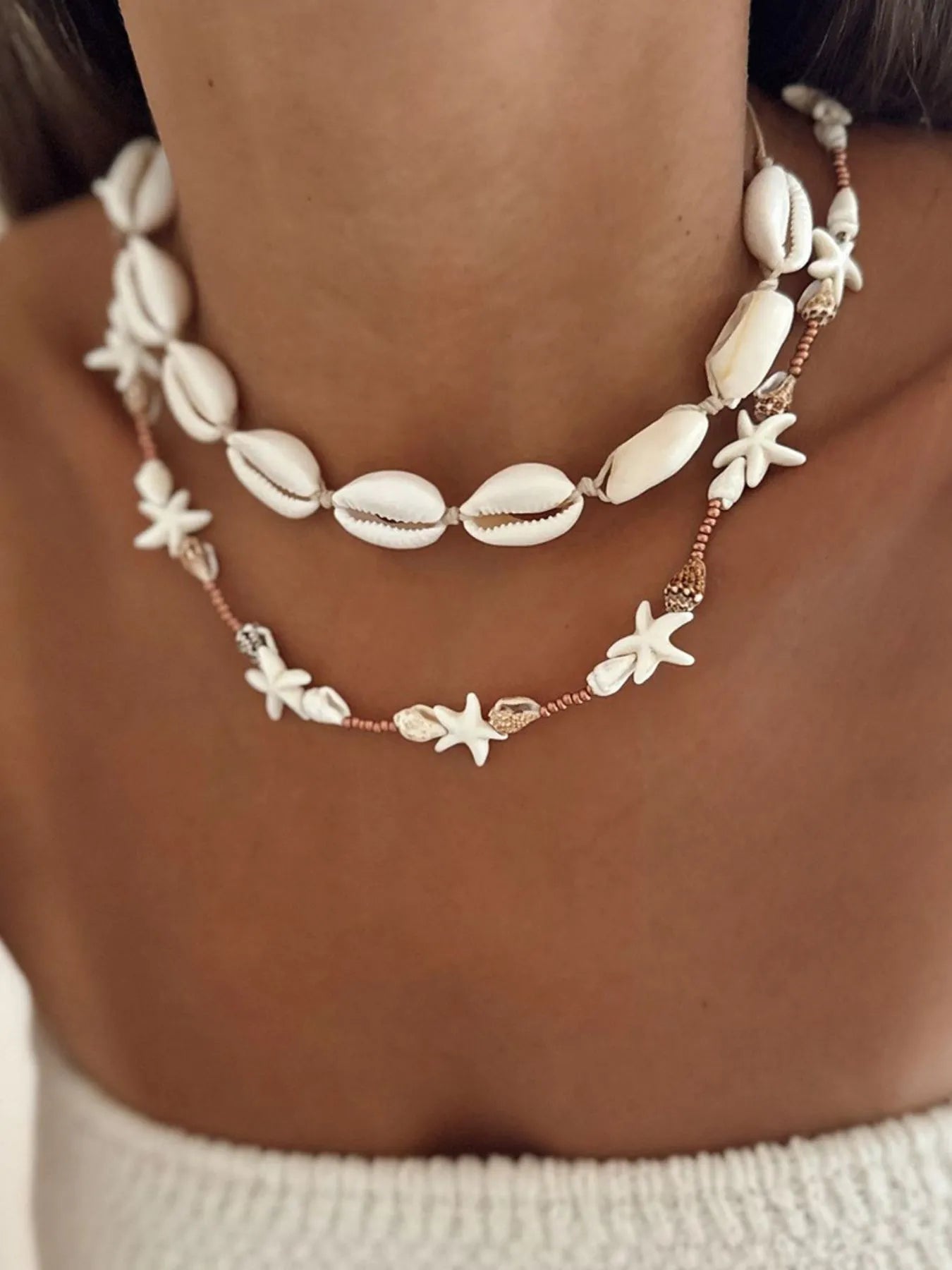Necklace with shell and starfish designs on a person's neck