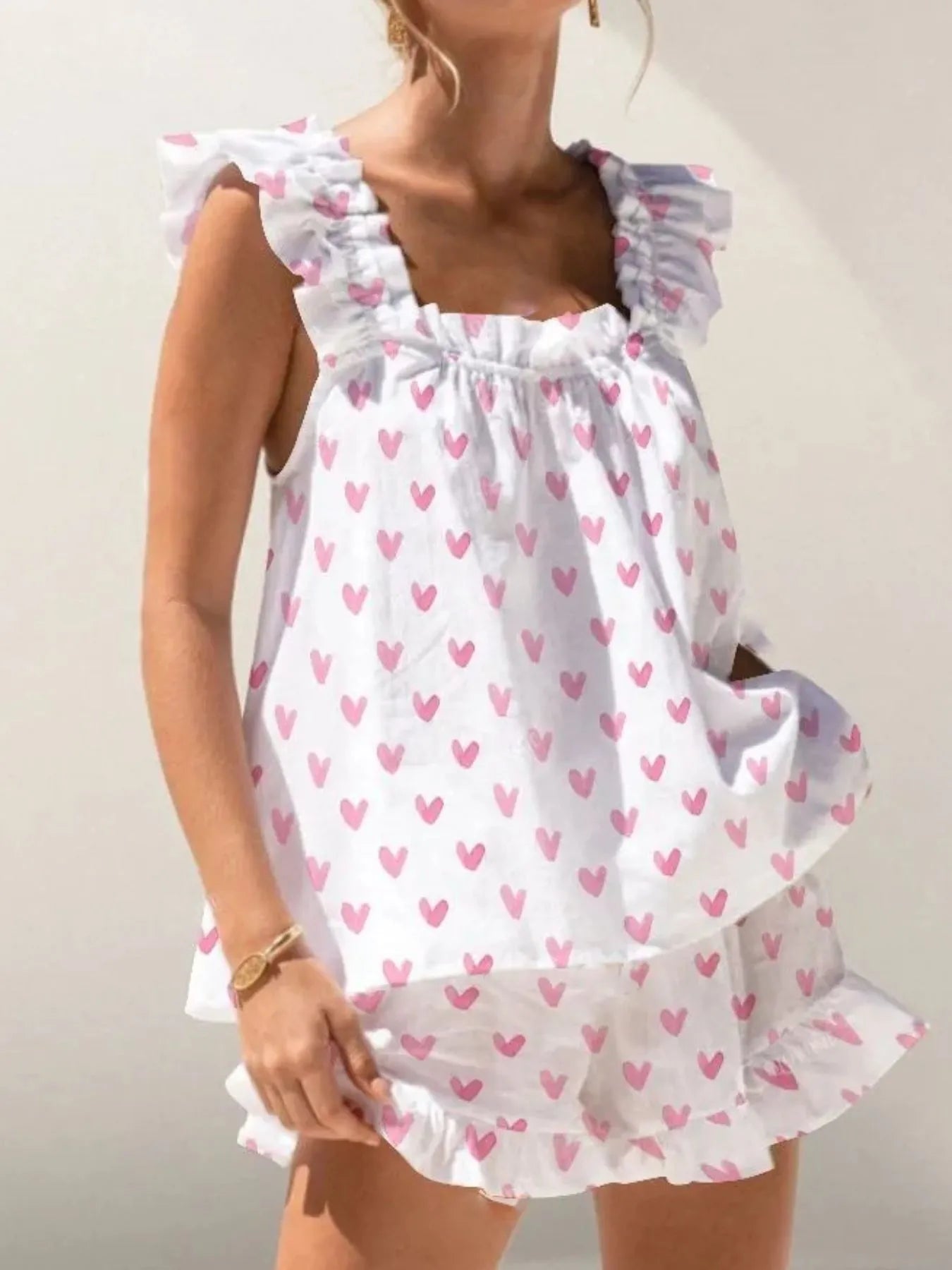White dress with pink heart patterns worn by a person on a plain background
